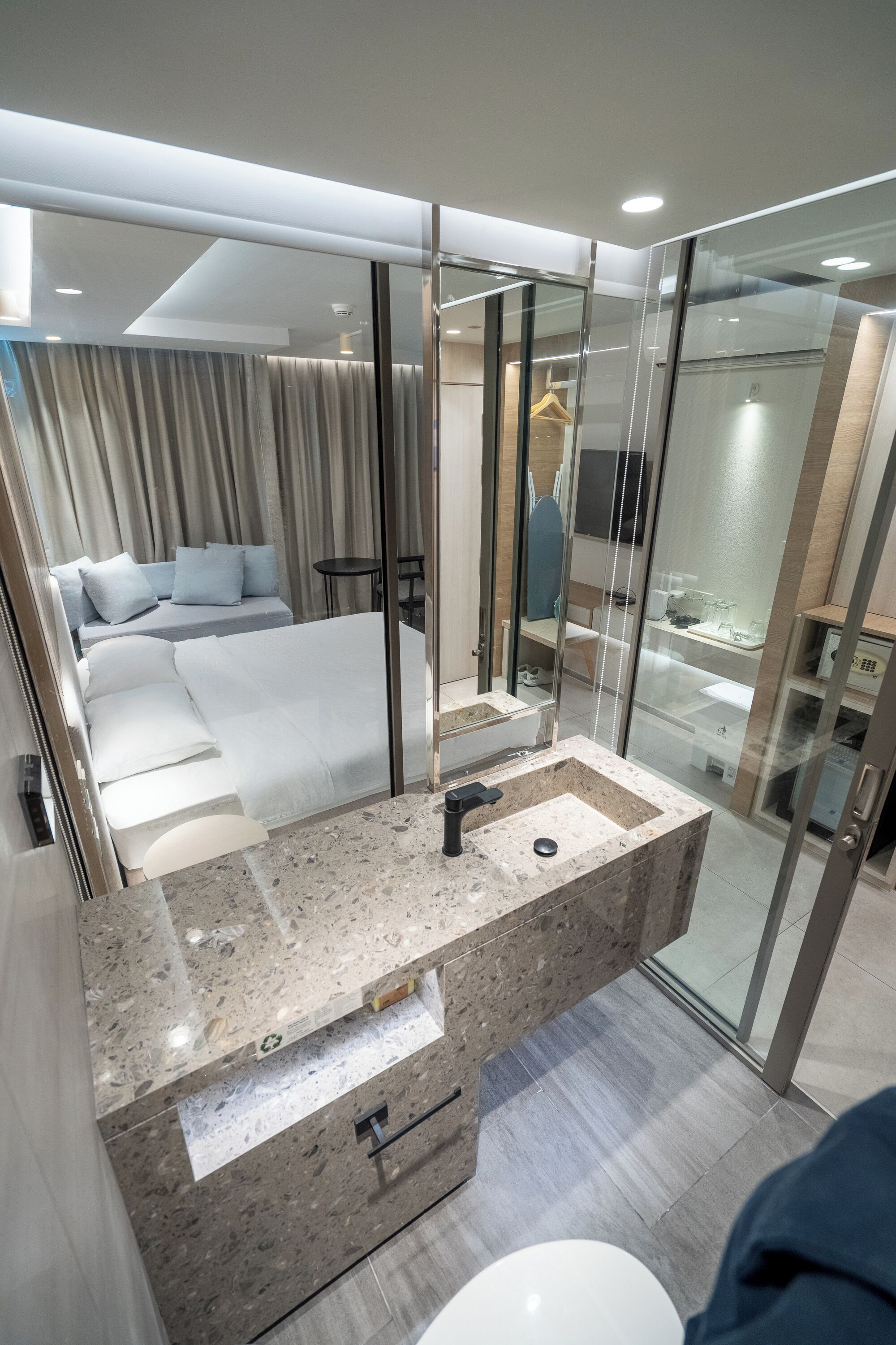 A modern bathroom with a glass shower enclosure, a marble sink, and a large mirror.