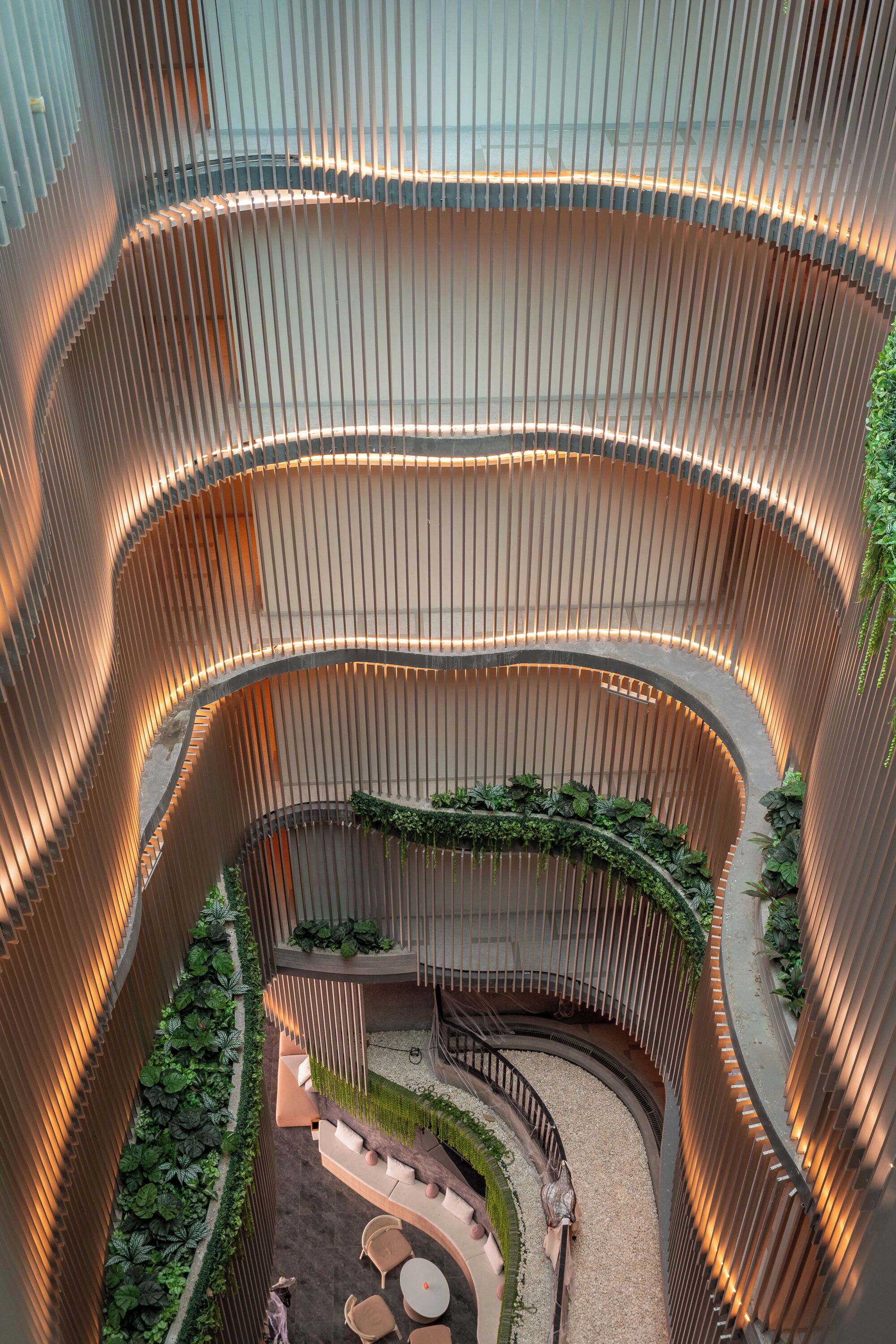 A multi-level atrium with curved wooden railings, a central garden area, and seating arrangements.