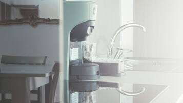 Eine moderne Küche mit Kaffeemaschine, Spüle und einem Essbereich mit Tisch und Stühlen.