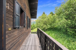 A wooden balcony with a view of a lush green landscape and a mountain in the distance. - Casa Stefania (Livigno)