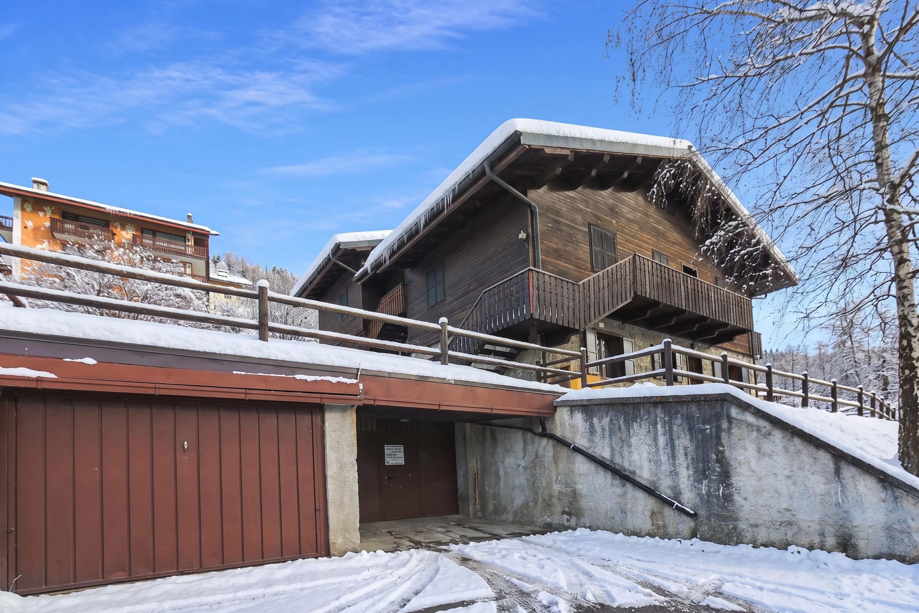A two-story wooden building with a snow-covered roof and a balcony.