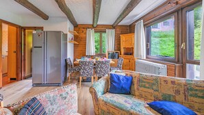 A cozy cabin interior with a dining area, a sofa, and a refrigerator.