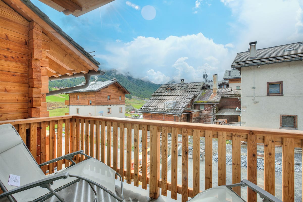 A wooden balcony with a view of traditional buildings and mountains.