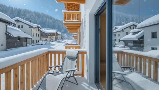 A balcony with wooden railings and two lounge chairs, overlooking a snow-covered village and mountains. - Leba 3 (Livigno)