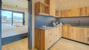 A modern kitchen with wooden cabinetry, a built-in oven, and a large window overlooking a cityscape. - Leba 3 (Livigno)