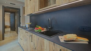 A modern kitchen with wooden cabinets, a black sink, and a cutting board with vegetables and bread. - Leba 2 (Livigno)