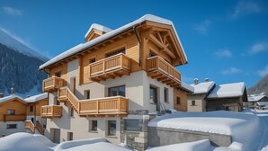 A multi-story wooden chalet with balconies, set in a snowy mountainous area. - Leba 2 (Livigno)