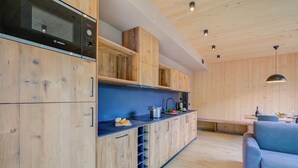 Eine moderne Küche mit Holdekor, einem integrierten Backofen und einem Essbereich mit einer Bank und einer Couch.