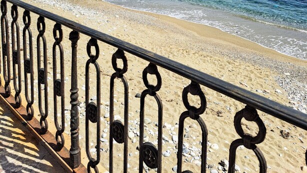A coastal beach with a metal railing, clear blue water, and rocky cliffs in the background. - Vigna dell`Etna - Piedimonte Etneo (Piedimonte Etneo)