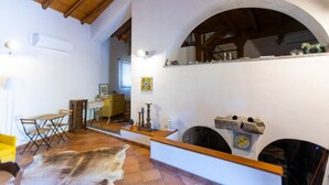 A rustic interior with a wooden ceiling, a stone fireplace, and a dining area with a yellow chair and a table. - Vigna dell`Etna - Piedimonte Etneo (Piedimonte Etneo)