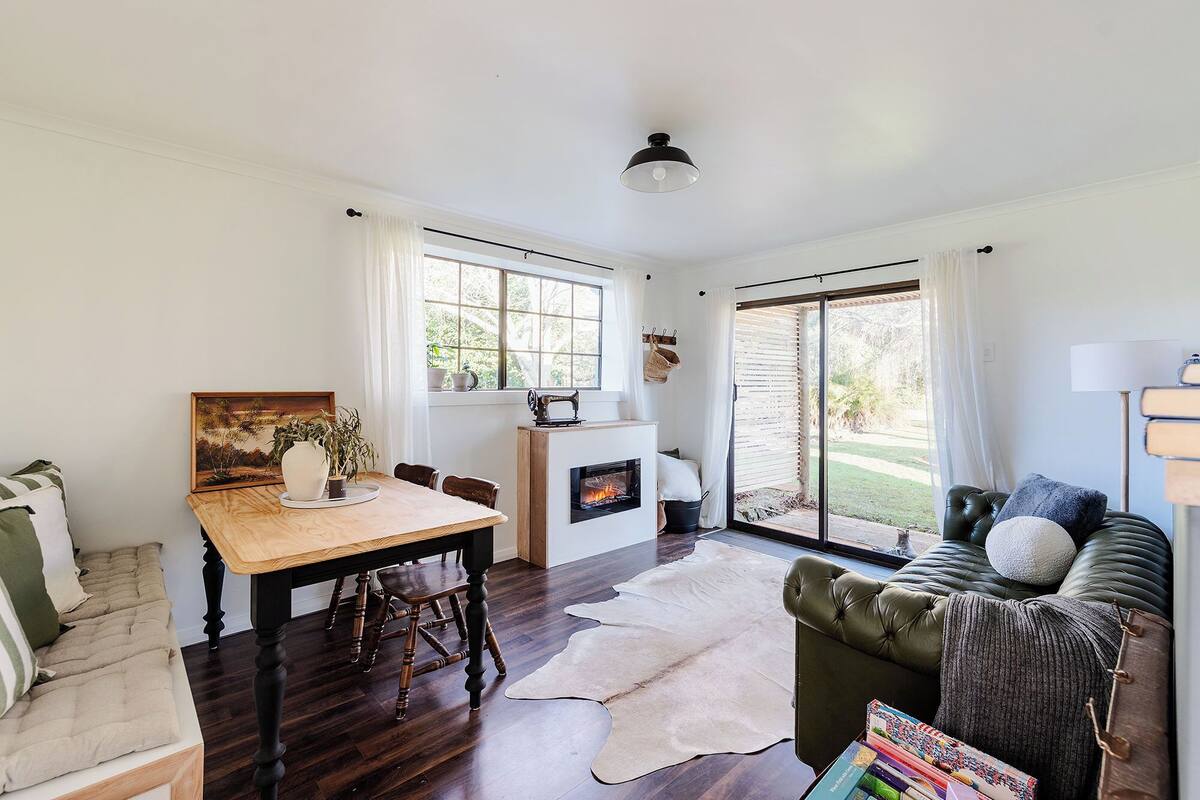 A cozy living room with a fireplace, a dining table, and a leather sofa.