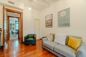 A living room with a sofa, a green armchair, and artwork on the wall.