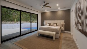 A modern bedroom with a large window, a ceiling fan, and a bed with a headboard. - Valea Estate - Secluded Beverly Hills Retreat 1-acre Oasis (Beverly Hills)