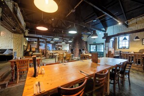 A spacious restaurant with high ceilings, exposed beams, and a large brick oven. Tables are set with cutlery, and the space is well-lit with pendant lights. - The Tolgus Inn at Tricky's (Redruth)