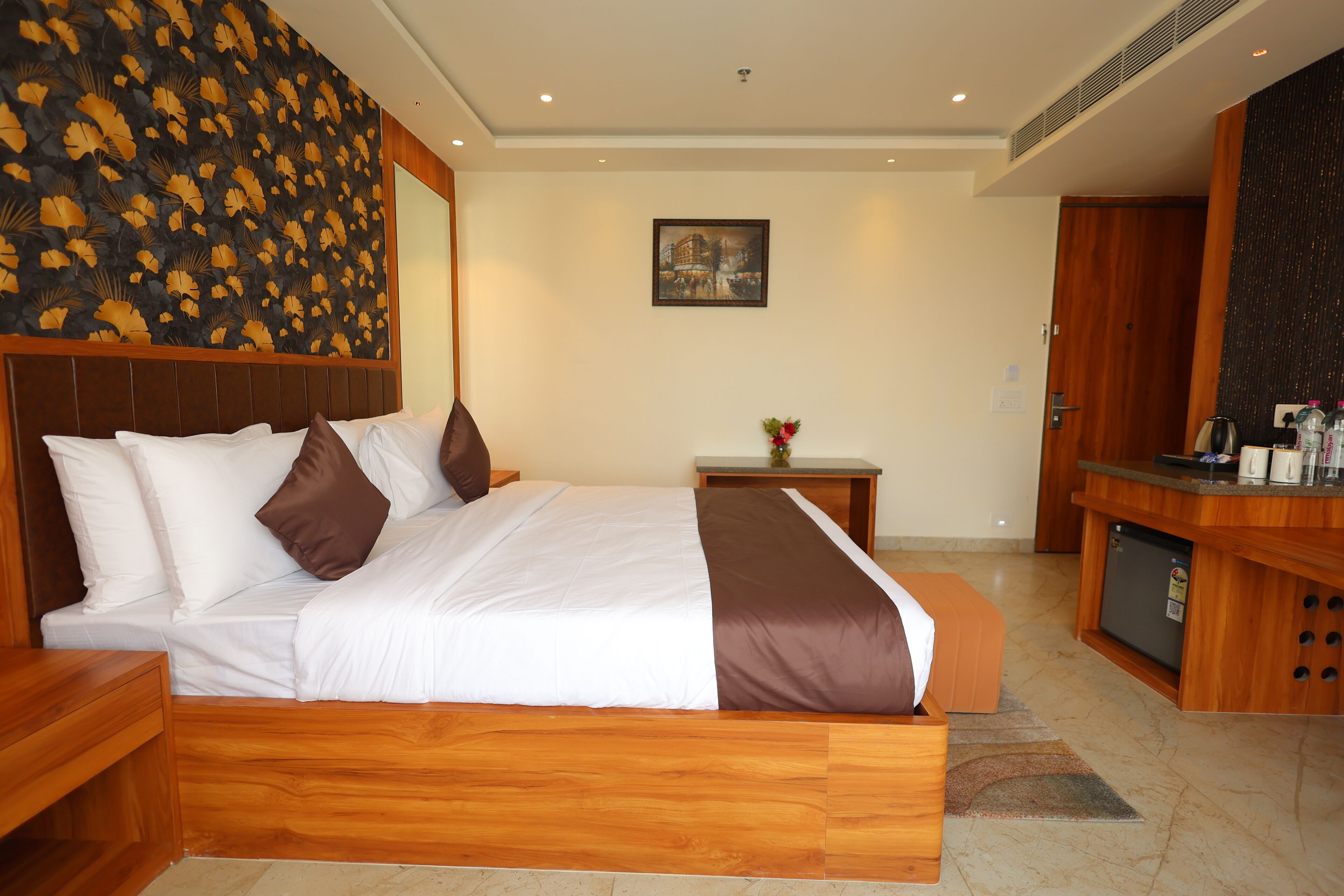 Ein Hotelzimmer mit einem hölzernen Bett, einem kleinen Tisch mit einer Vase und einer Küchenzeile.