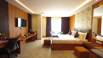 A modern hotel room with a bed, desk, and seating area.