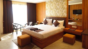 Quarto de hotel moderno com uma cama grande, uma escrivaninha, uma cadeira e uma TV fixada na parede.