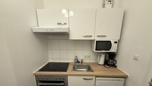 A compact kitchen with a stove, oven, microwave, and a sink. - Smart 1BR Apt Near Westbahnhof Station (Vienna)