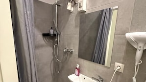 A bathroom with a shower, a sink, a hairdryer, and a toilet. - Smart 1BR Apt Near Westbahnhof Station (Vienna)