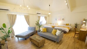 Une chambre d’hôtel moderne avec un canapé gris, une petite table basse et un lit agrémenté d’oreillers jaunes.