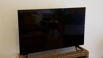 A flat-screen TV on a glass-top stand against a white wall.