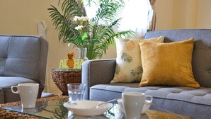 Un salon avec un canapé gris, une table basse en verre et une plante décorative.