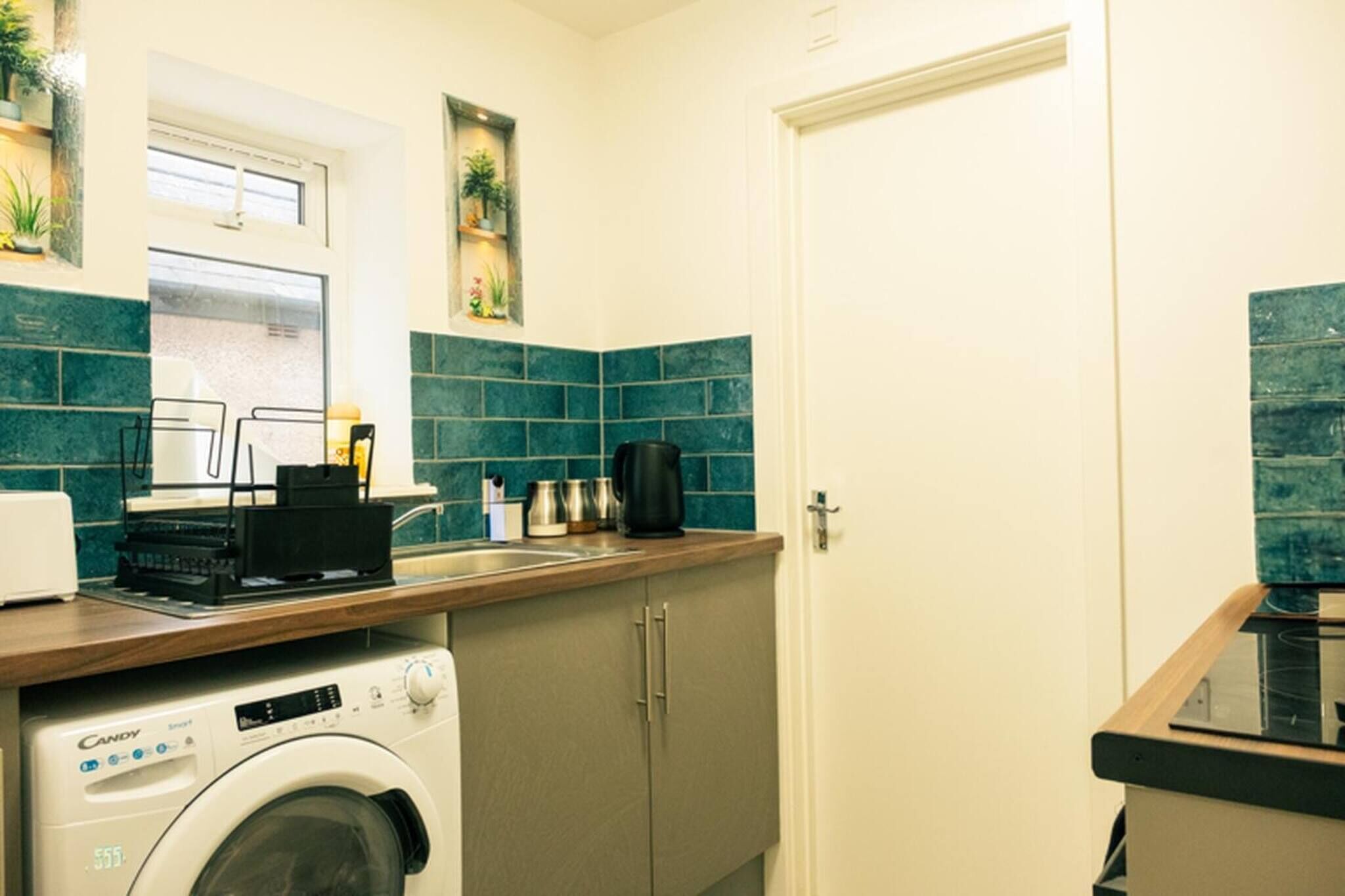 Une cuisine compacte équipée d’un lave-linge, d’une machine à café et d’un four à micro-ondes.