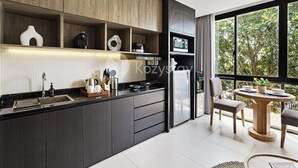 A modern kitchen with dark cabinetry, a built-in oven, and a dining area with a round wooden table and chairs. - Caraya by Kozystay - Nusa Dua (Nusa Dua)
