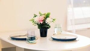 Ett bord med en vas med blommor, två glas och en tallrik.