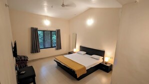 Quarto com cama, escrivaninha, cadeira, janela com cortinas e ventilador de teto.