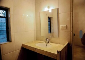 A bathroom with a sink, mirror, and a window with patterned glass. - Hifi Private Villa (Nagaon)