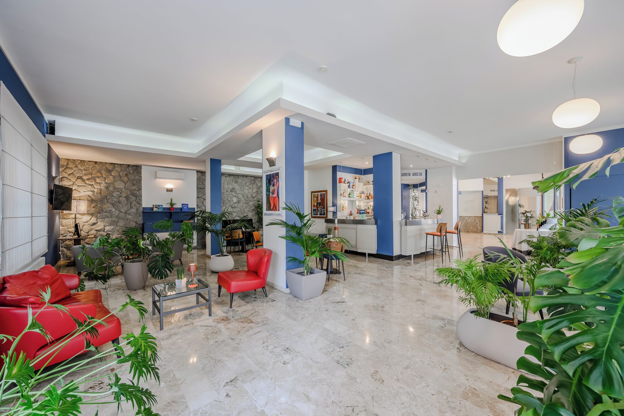 A spacious lobby with a stone wall, a reception desk, and a bar area.