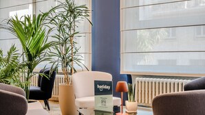 Un moderno vestíbulo de hotel con zona de estar, ventanas amplias y mostrador de recepción.