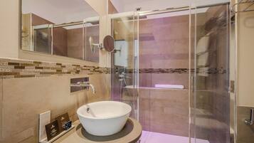Un baño moderno con ducha envuelta en vidrio, un lavamanos grande de color blanco y un salpicadero de azulejos.