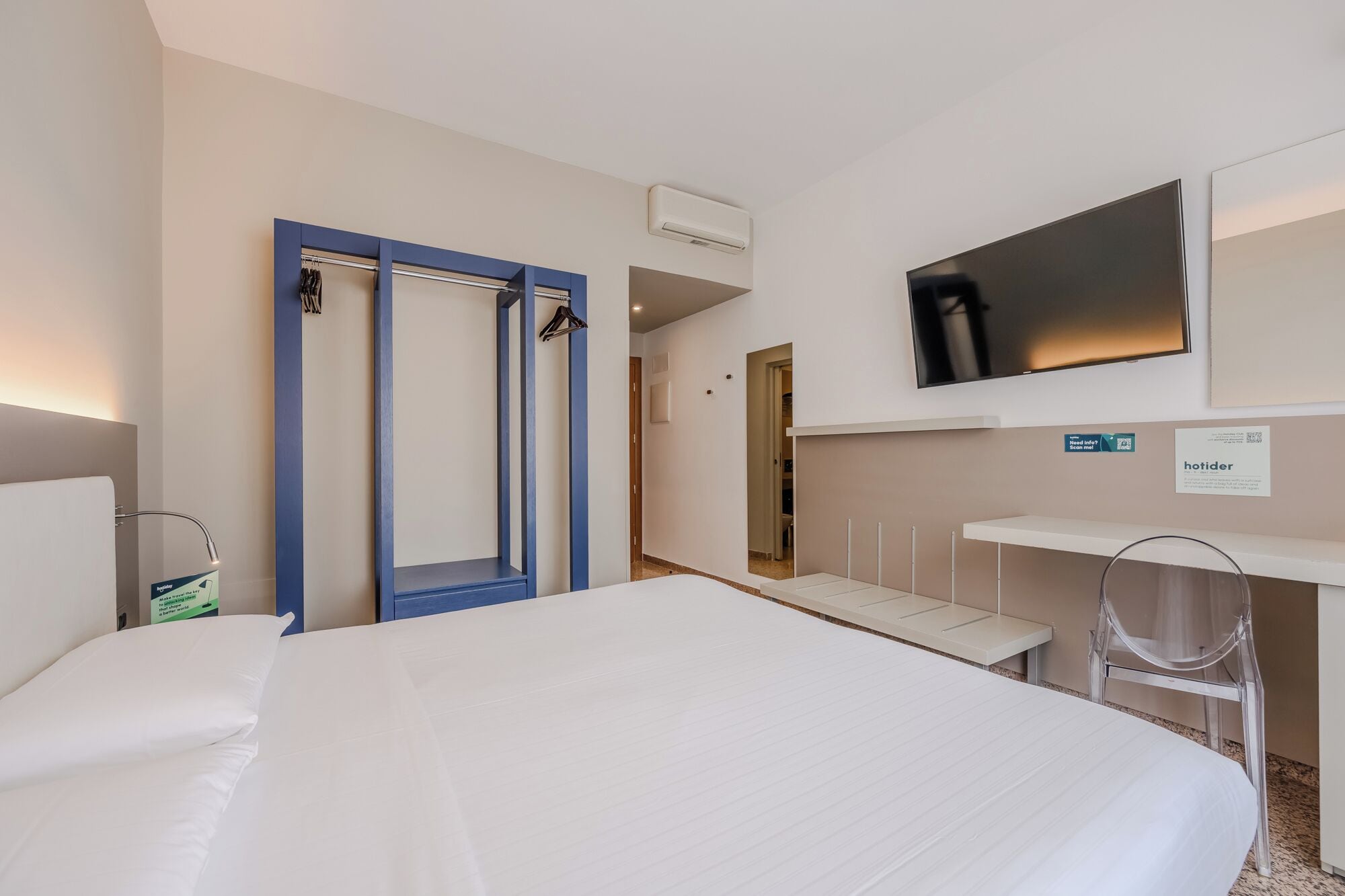 Une chambre d’hôtel équipée d’un lit, d’un bureau, d’une télévision et d’une armoire.