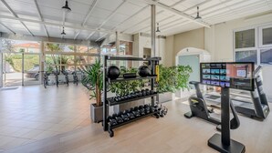 Un gimnasio con equipo de ejercicio, una cinta de correr y una pantalla digital que muestra rutinas de entrenamiento.