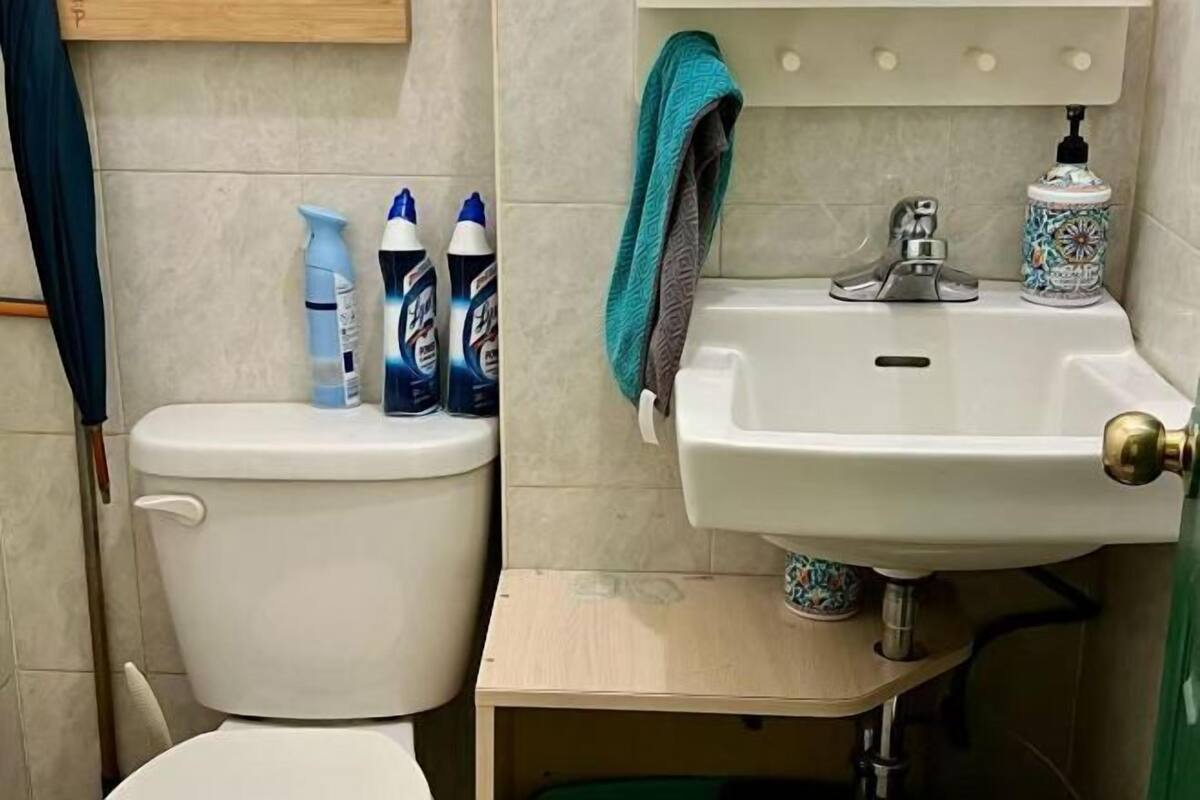 A bathroom with a toilet, a sink, and two bottles of cleaning products on the wall.