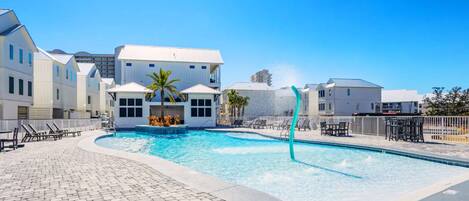 A swimming pool with a fountain, surrounded by lounge chairs and a paved walkway.