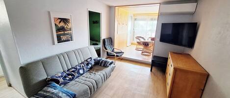 A modern living room with a grey sofa, a wooden cabinet, and a flat-screen TV.