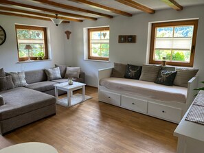 A cozy living room with a sofa, a coffee table, and a window with a view of greenery.