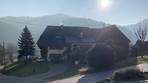 A house with a sloped roof, a chimney, and a driveway leading to a parked car. - Apartment 'Haus Dekostüble' with Mountain View, Private Terrace and Wi-Fi (Münstertal)