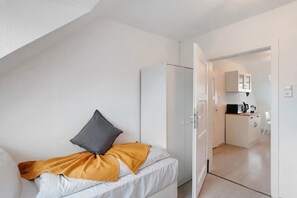 Una habitación pequeña con cama, armario y kitchenette.