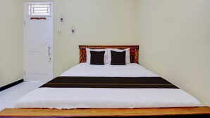 A single-bed room with a wooden headboard, white bedding, and a closed door. - OYO 94841 Alodia Homestay Family (Kejajar)
