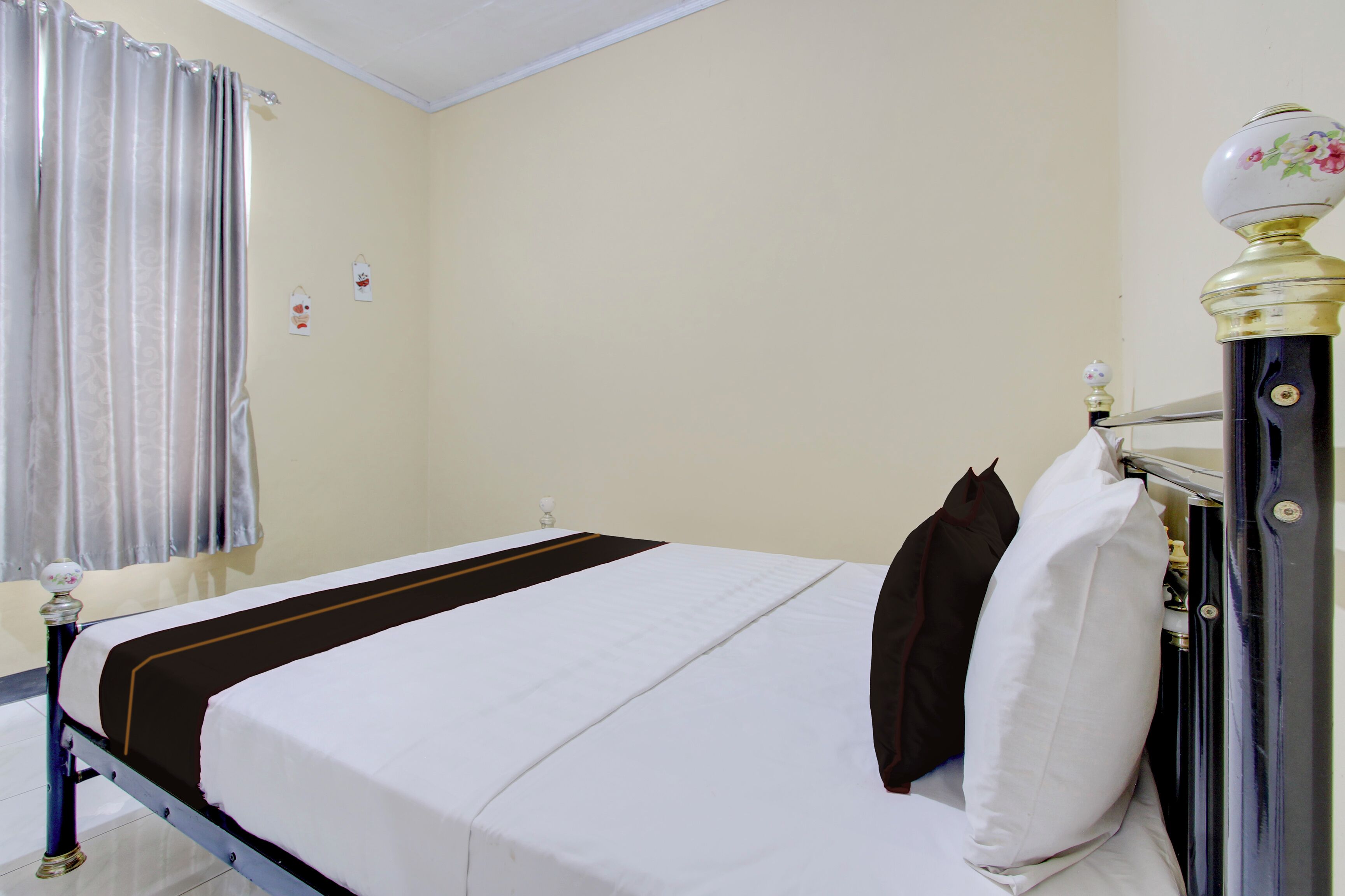 Ein Zimmer mit Bett, Nachttisch, Lampe und einem fenster mit Vorhängen.