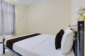 A room with a bed, a nightstand, a lamp, and a window with curtains. - OYO 94841 Alodia Homestay Family (Kejajar)