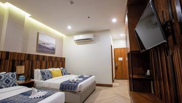 A hotel room with two beds, a flat-screen TV mounted on the wall, an air conditioning unit, and a wooden panel wall.