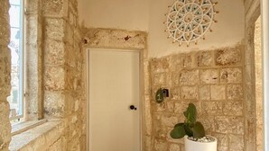 A narrow stone-walled hallway with a white door, a decorative ceiling medallion, and a potted plant. - Borgo Sant' Angelo exclusive house Room 1 (Conversano)