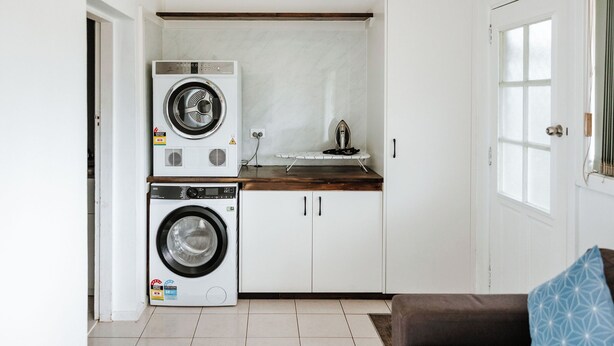 A compact kitchen with a washing machine, an iron, and a wooden countertop. - The Waratah Escape Nowra (Nowra)