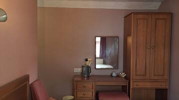 A hotel room with a bed, a desk, a wardrobe, and a mirror.