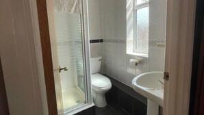 Egy fürdőszoba zuhanyzóval, WC-vel és mosdókagylóval.